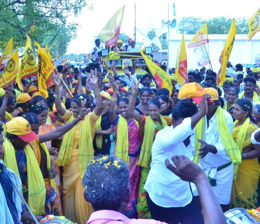 Supporters in yellow scarves and caps dancing beside a campaign vehicle during a roadshow