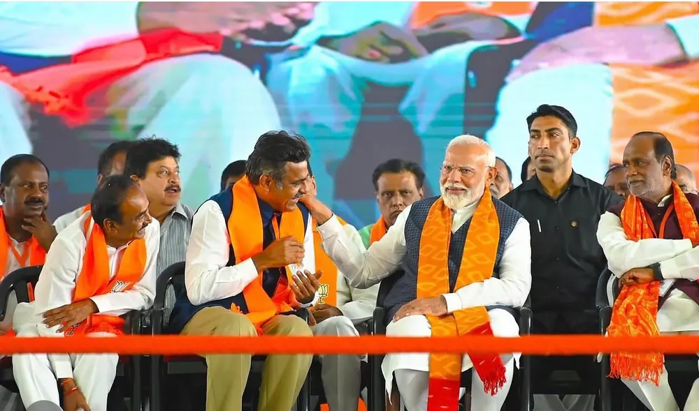 Leaders in saffron scarves seated together on a stage
