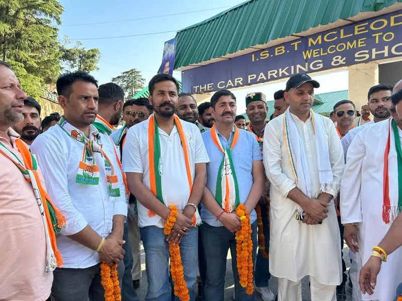 Supporters wearing garlands and scarves at a bus stand entrance