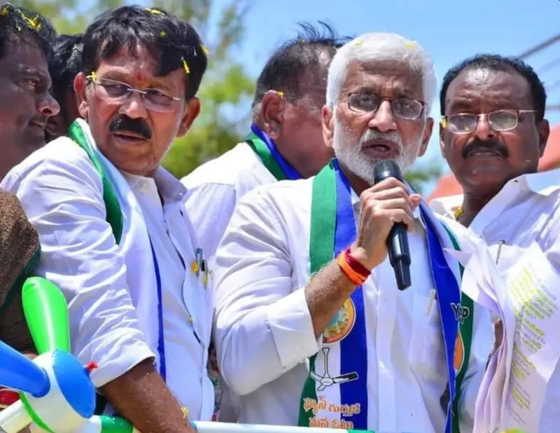 A speaker addressing a roadside gathering from a campaign vehicle, with supporters in scarves around him